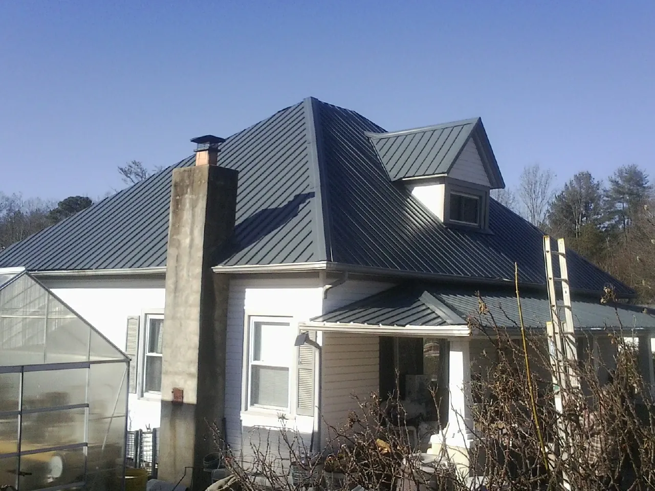 Dark blue standing seam metal roof on a white farmhouse with dormer — Slate & Tile Roof Repair by Roofing Brothers in Fairbanks
