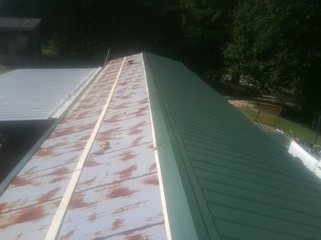 Old rusted panels beside newly installed green metal roofing — Wind Damage Roof Repair by Roofing Brothers in Fairbanks