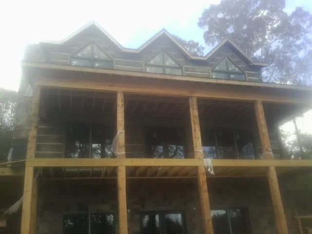 Dormers and porch framing on a large log home under construction — Roof Coating work by our crew in Fairbanks