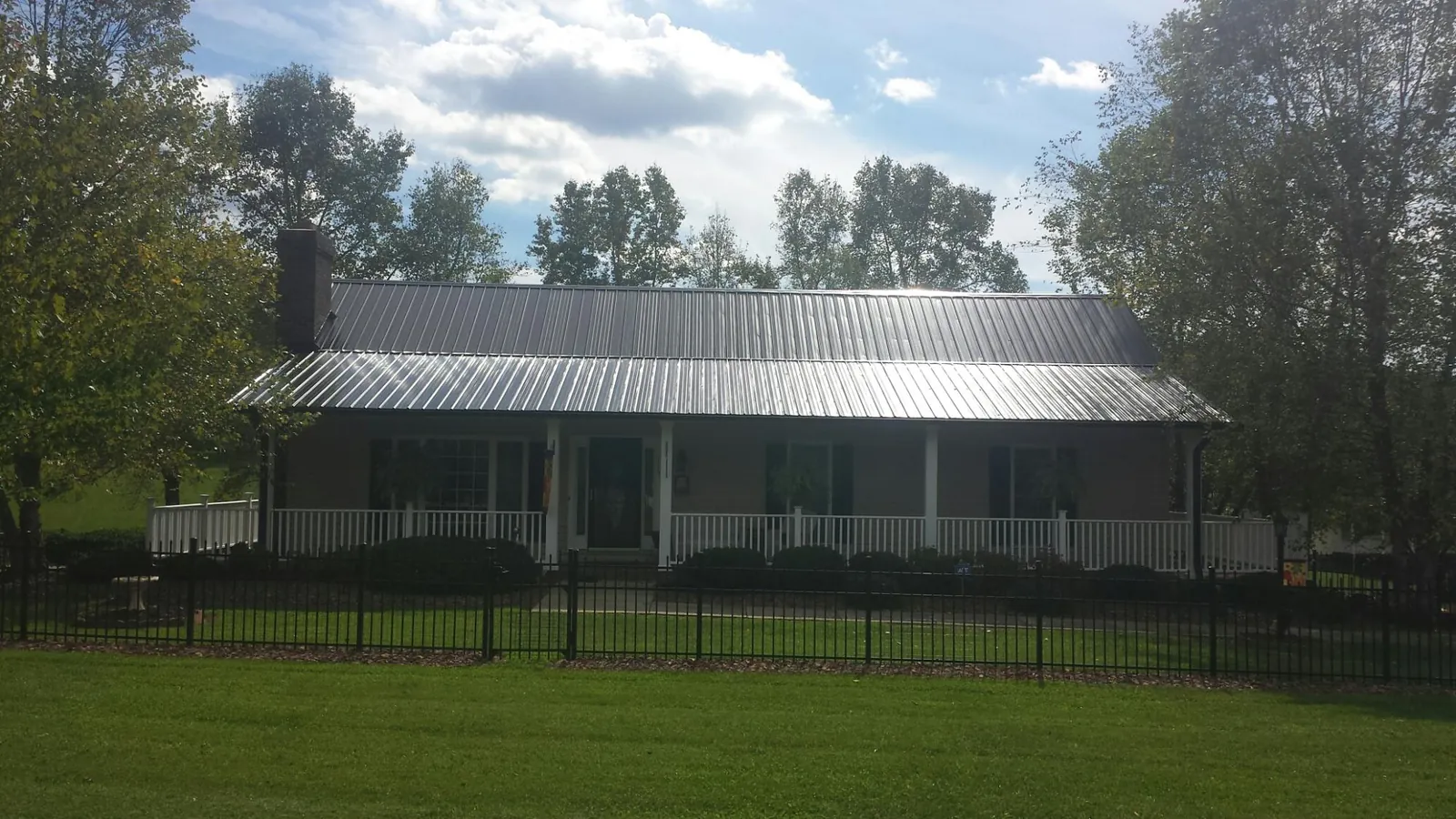 Gray metal roof on a brick ranch with a full width front porch — Gutter Guard Installation work by our crew in Fairbanks